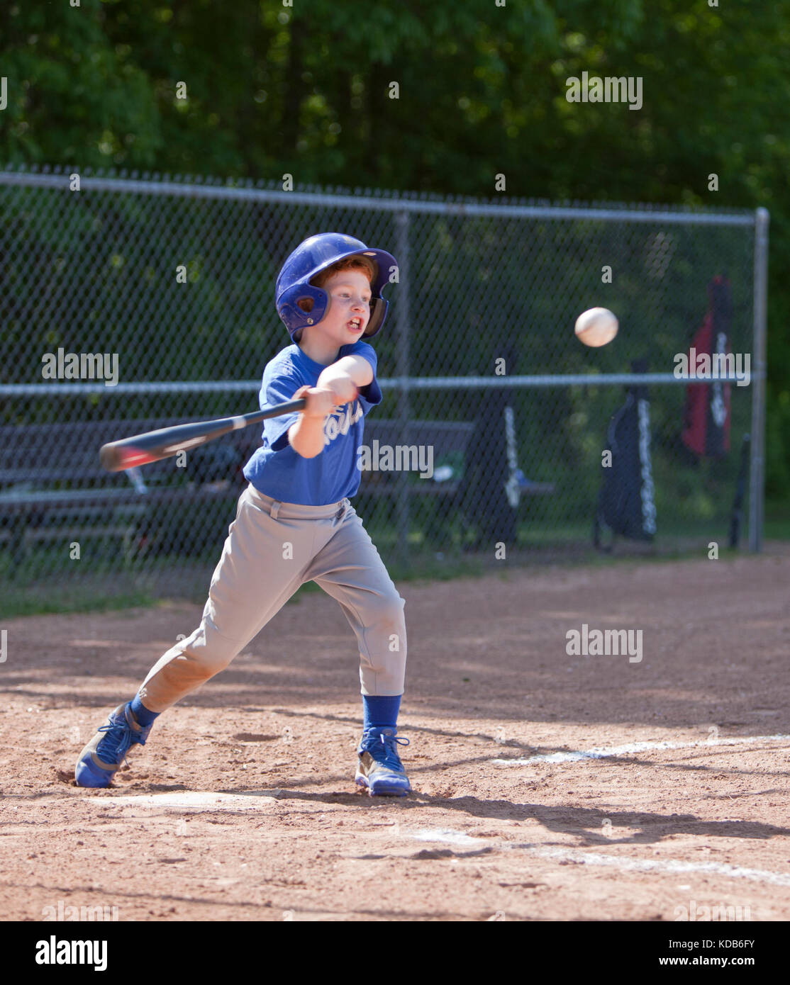 Boy hitting ball whilst playing baseball in a blue uniform Stock Photo