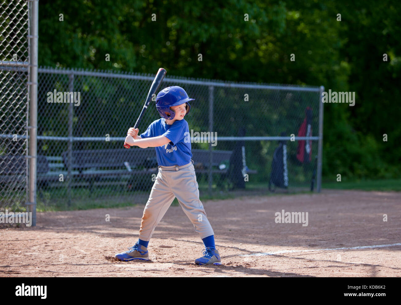 Boy hitting ball whilst playing baseball in a blue uniform Stock Photo