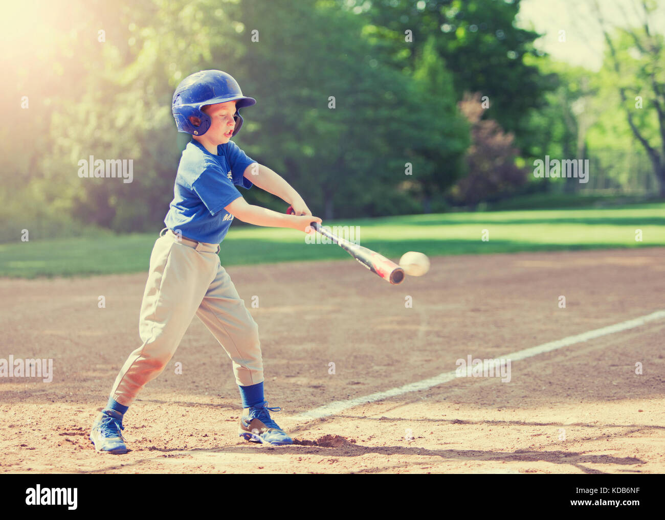 Boy hitting ball whilst playing baseball in a blue uniform Stock Photo