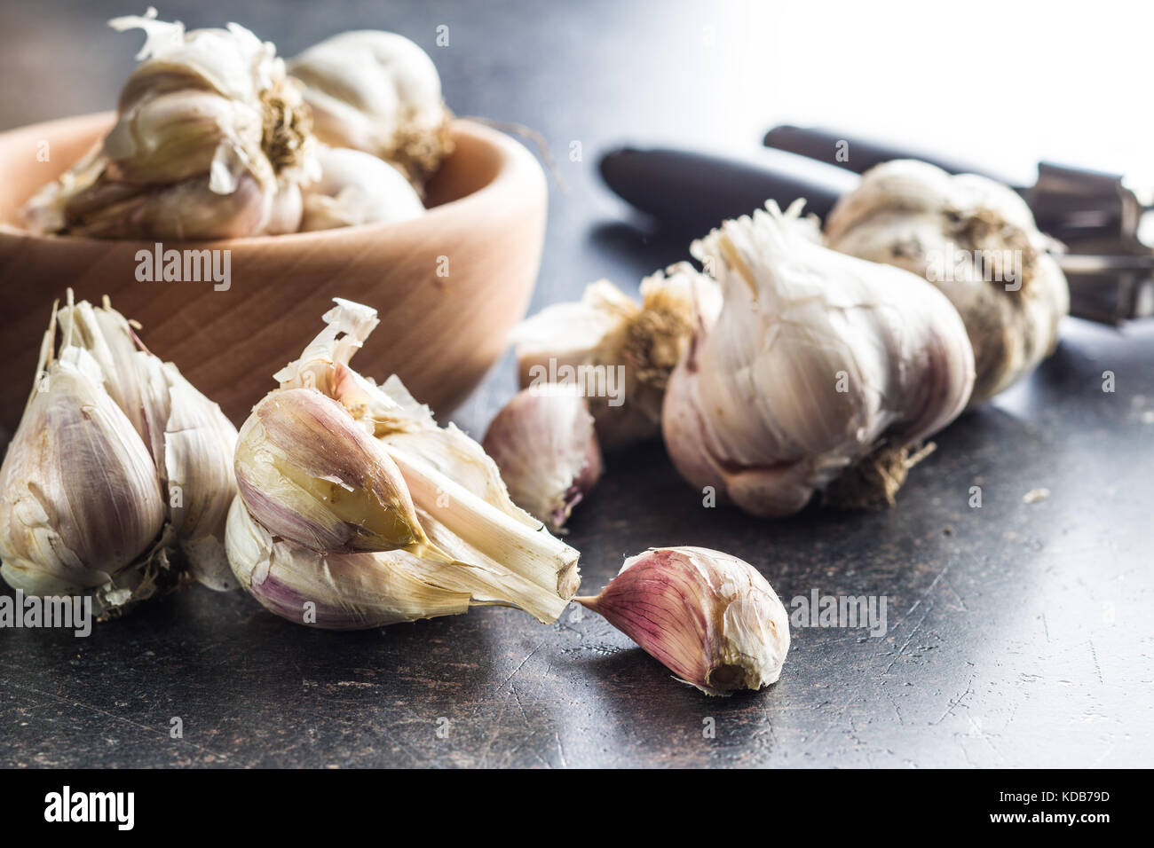 Fresh garlic and garlic presser on kitchen table. Stock Photo