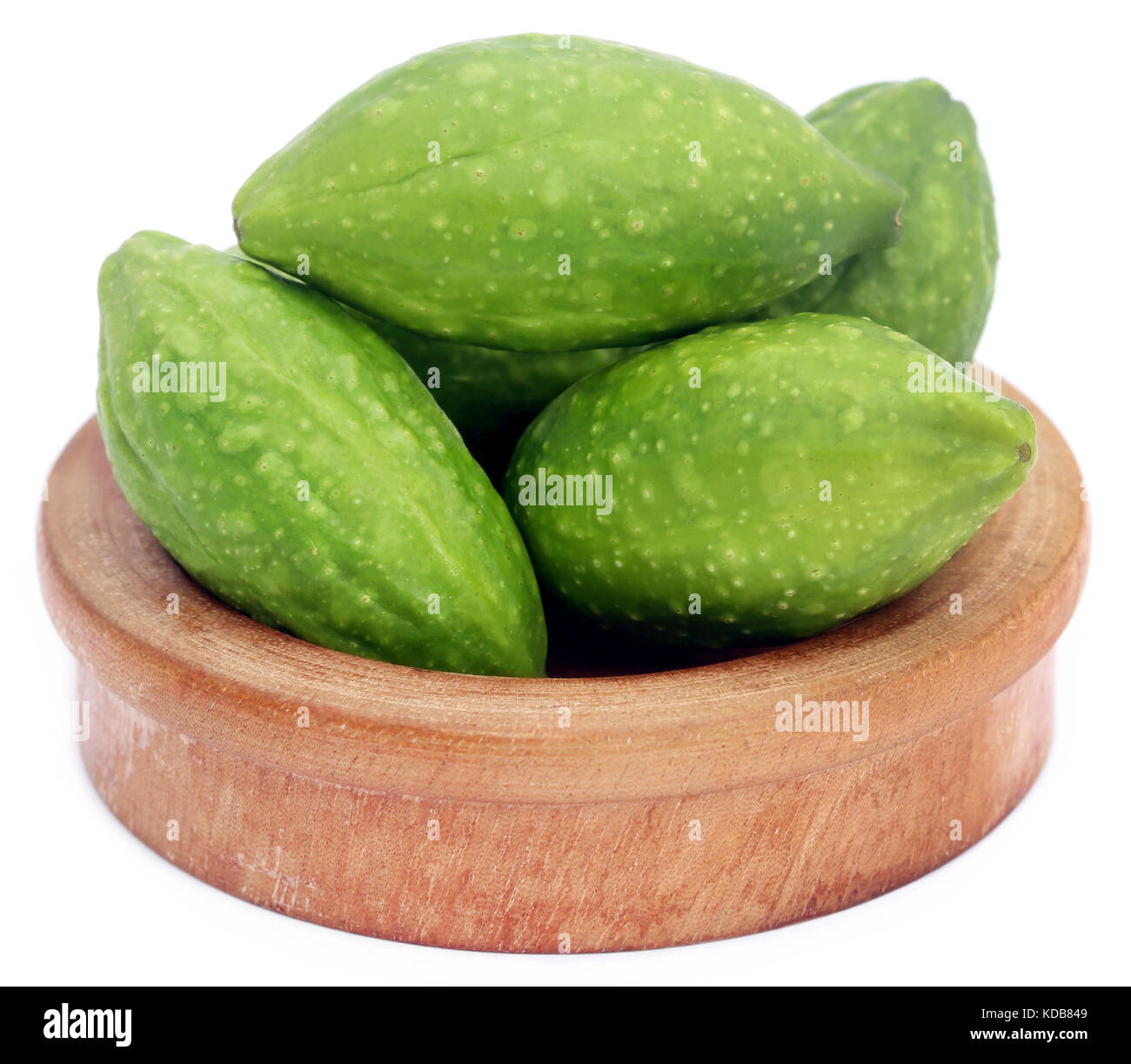 Fresh green medicinal haritaki fruits in a wooden bowl over white background Stock Photo