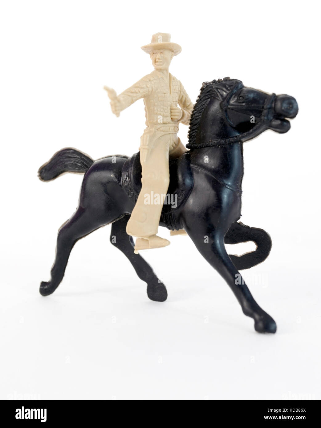 Plastic toy cowboy with pistol on black horse. Stock Photo