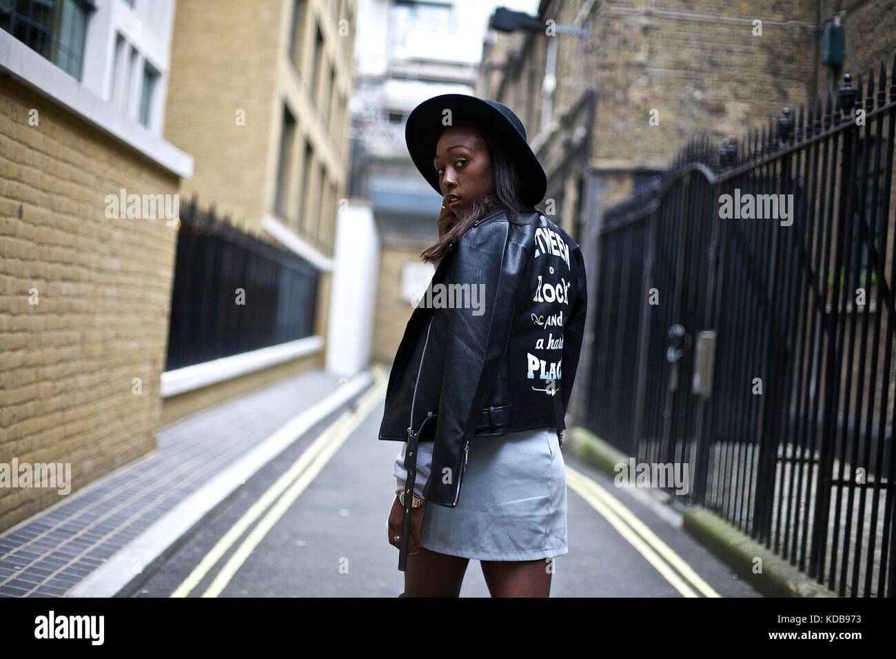 Fashionable blogger wearing wide rimmed hat and embellished leather jacket poses for shots during London Fashion Week . Sept 2016 Street style Stock Photo
