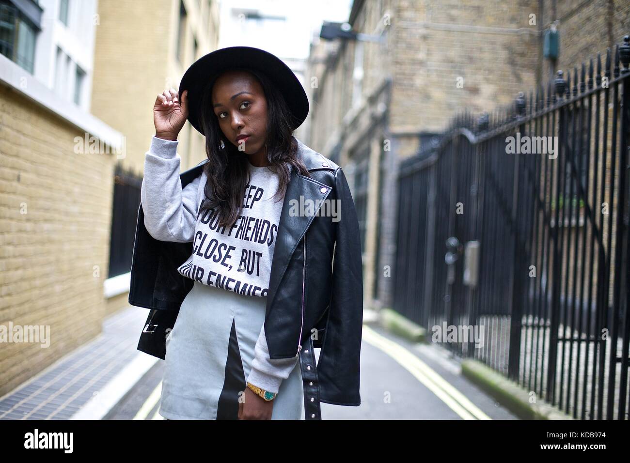 Fashionable blogger wearing wide rimmed hat and embellished leather jacket poses for shots during London Fashion Week . Sept 2016 Street style Stock Photo