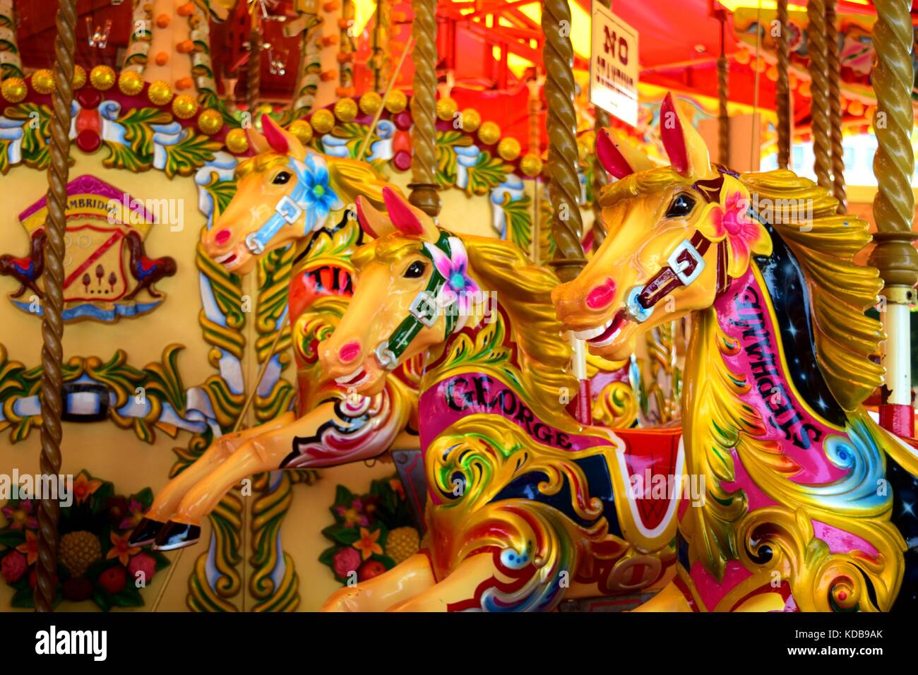 Three horses in line on an empty colourful carousel. Bright colours and patterns make the carousel look more beautiful and appealing. Smiling horses. Stock Photo