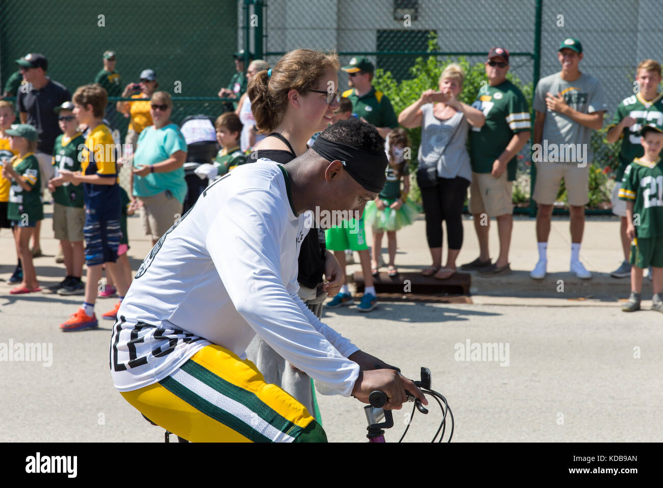Green Bay, WI - August 1, 2017:  Green Bay Packer Damarious Randall rides a young fans bike after football practice.  The community owned team has a l Stock Photo