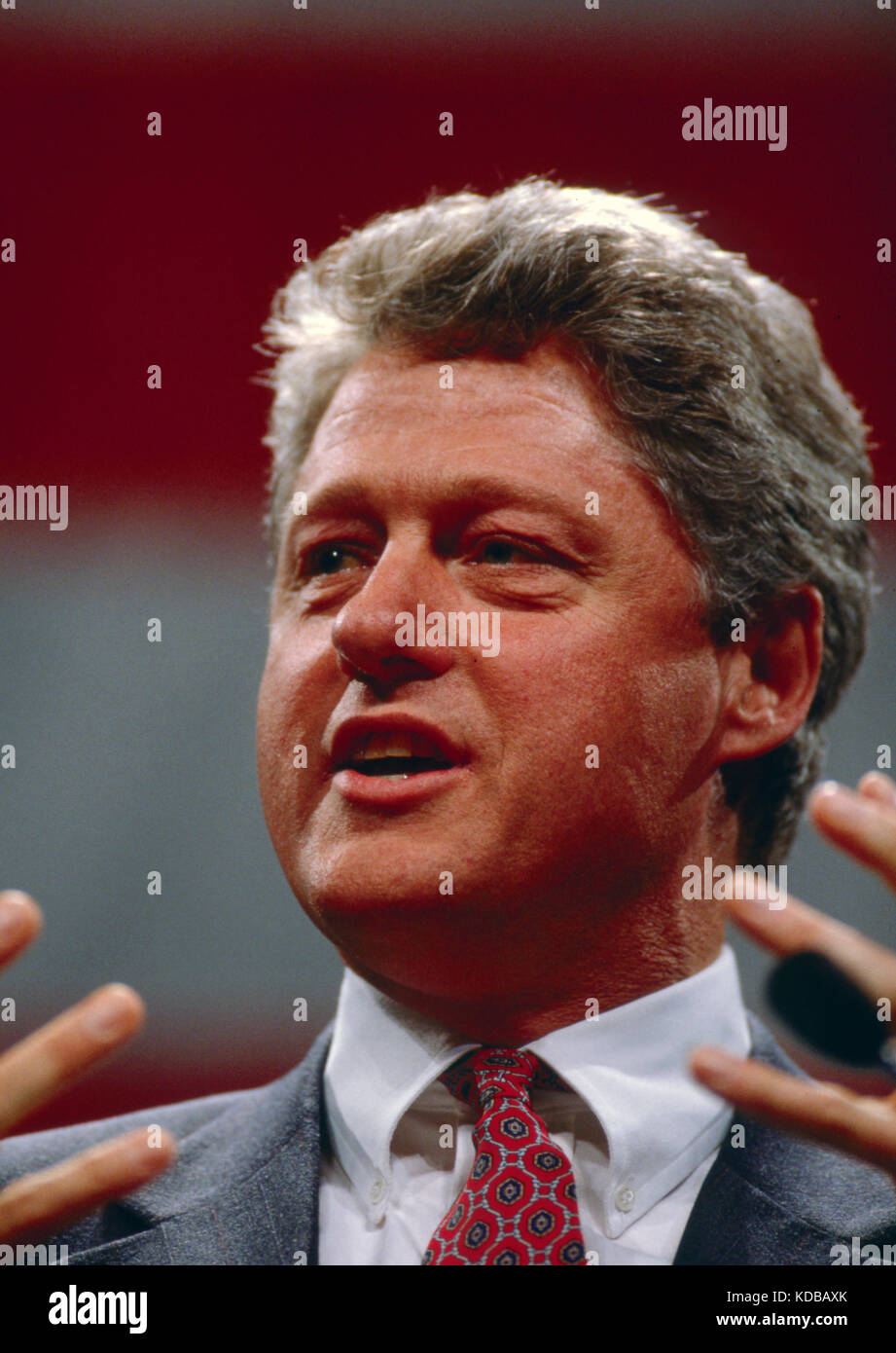President Bill Clinton while speaking. A large American flag hangs behind him. Stock Photo