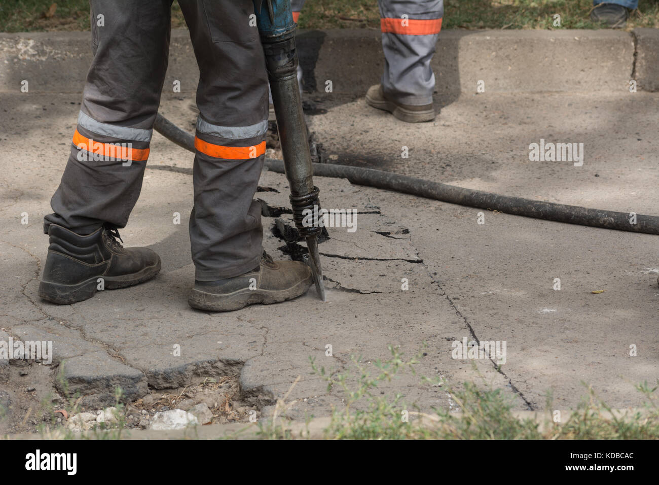 Road repairing works with jackhammer. Male worker using jackhammer