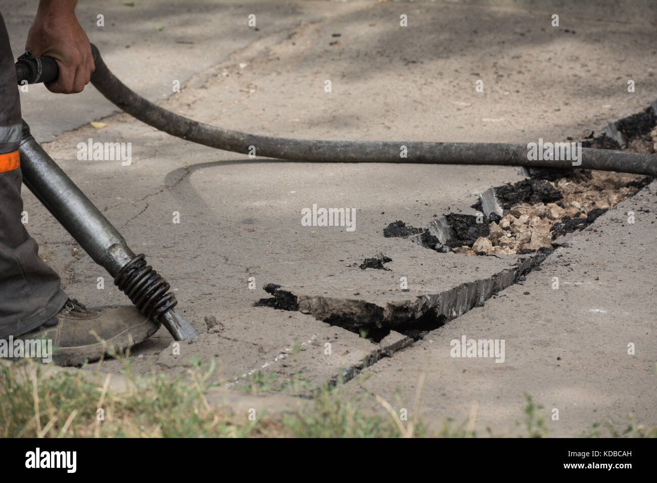 Road repairing works with jackhammer. Male worker using jackhammer