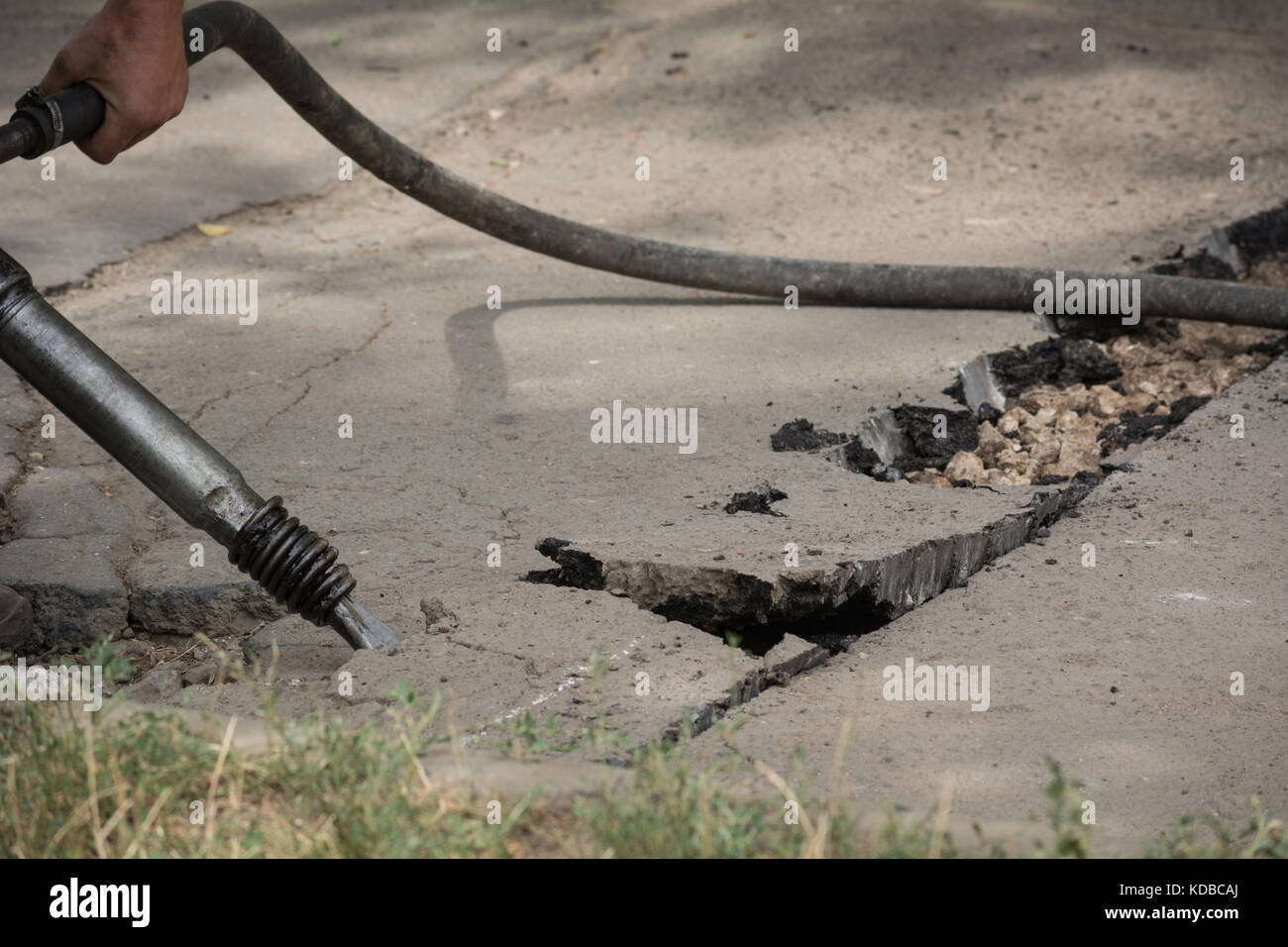 Road repairing works with jackhammer. Male worker using jackhammer