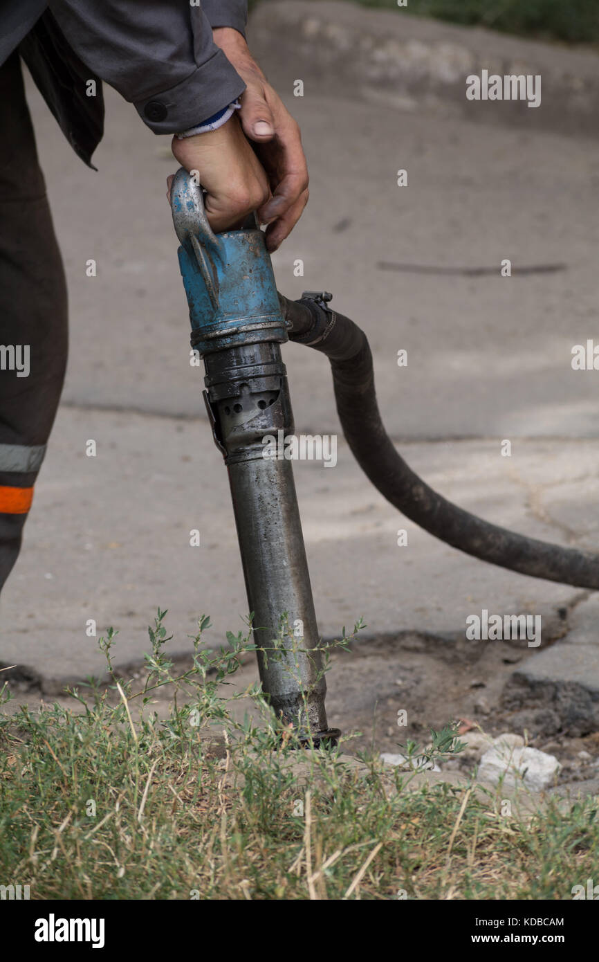 Road repairing works with jackhammer. Male worker using jackhammer