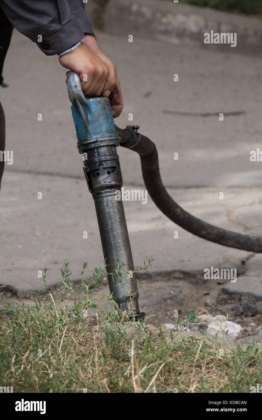 Road repairing works with jackhammer. Male worker using jackhammer