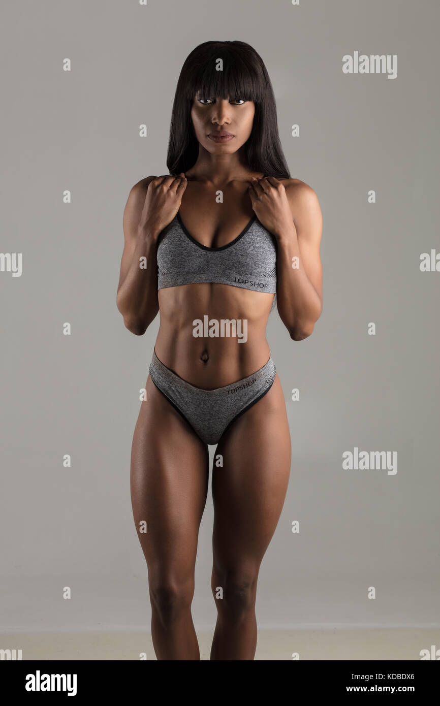 A beautiful Black fitness model photographed against a plain