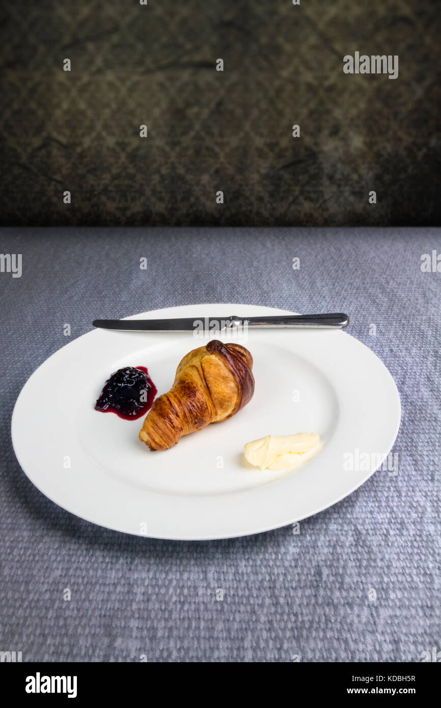 Croissant on a white plate with black cherry preserve and butter Stock Photo