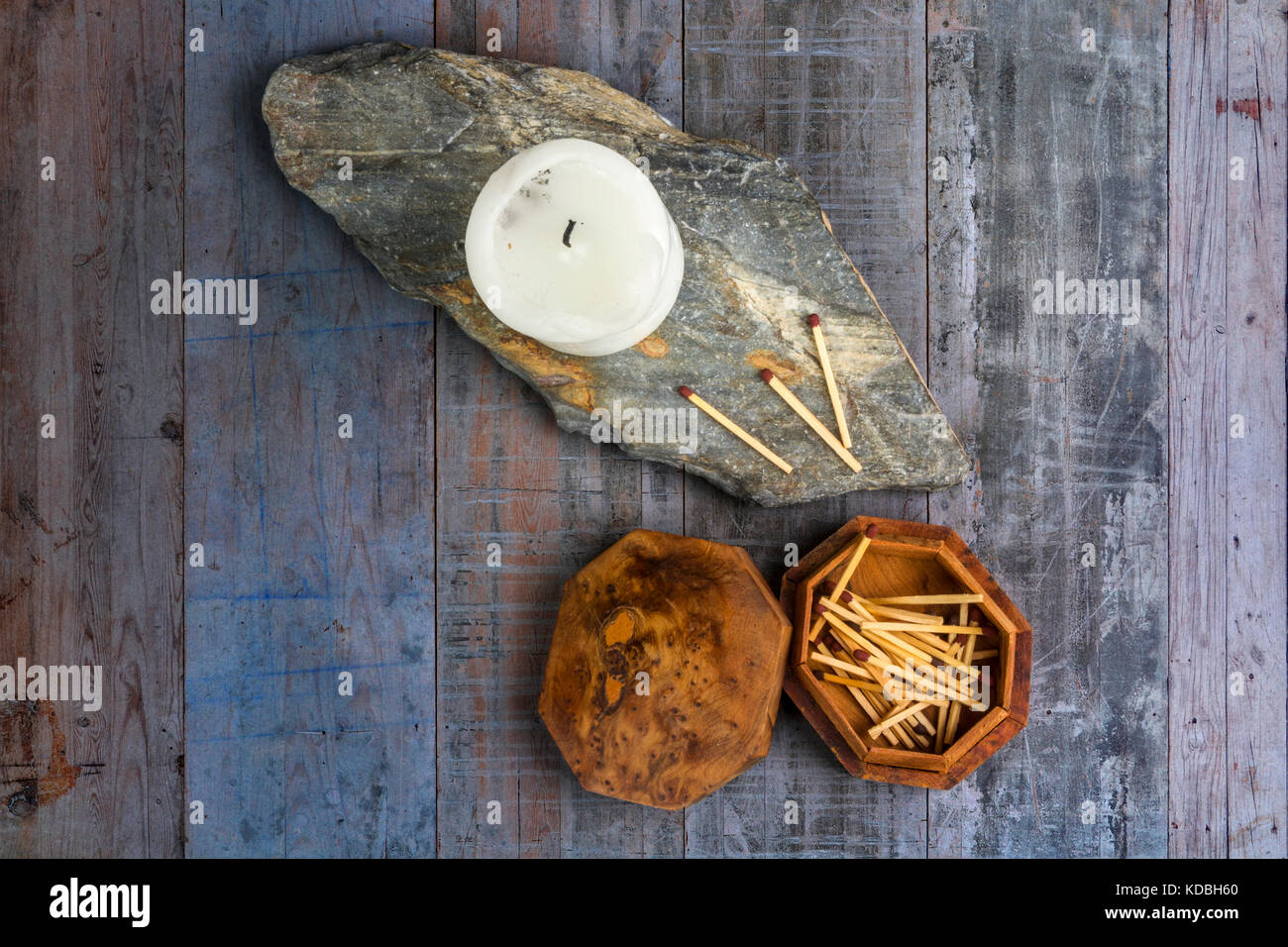 White church candle on a piece of slate with a wooden box of matches, on a wood plank background Stock Photo