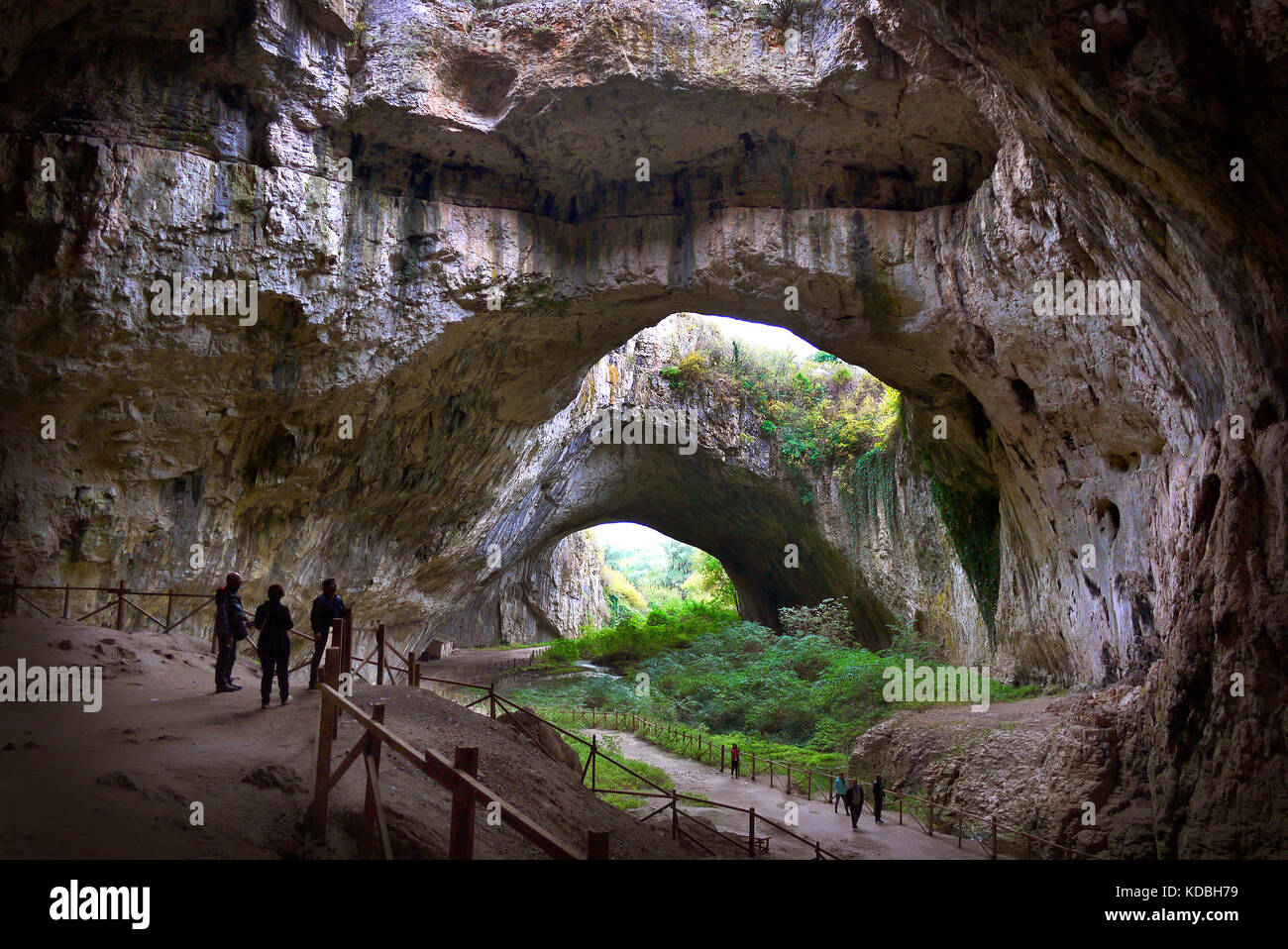 Visitors dwarfed by the size of the Devetashka Cave in Bulgaria. Stock Photo