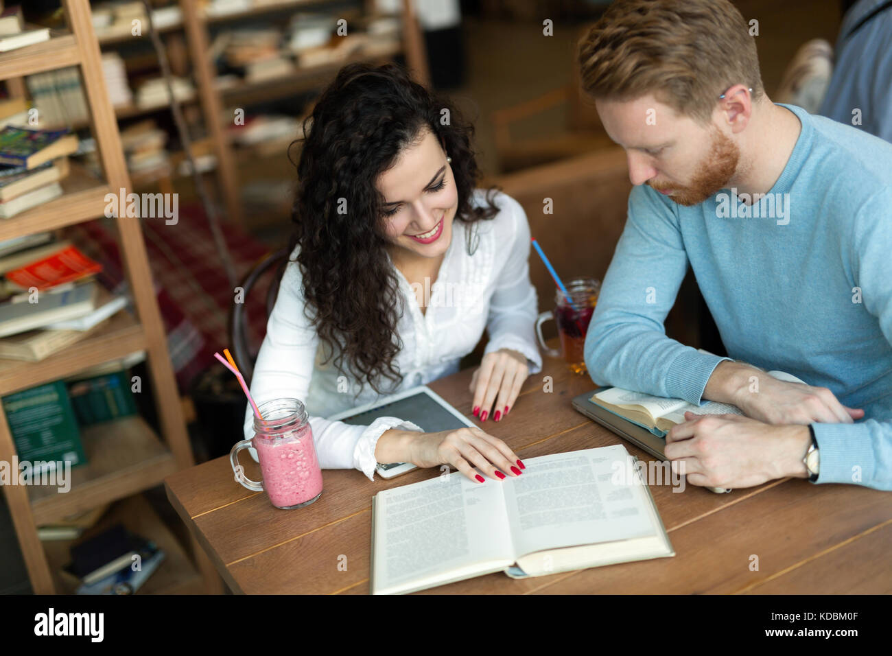 Young students spending time in coffee shop reading books Stock Photo