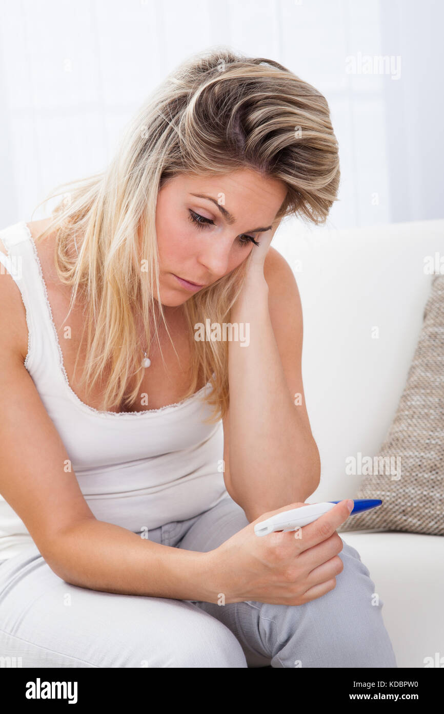 Worried young female checking pregnancy test at home Stock Photo