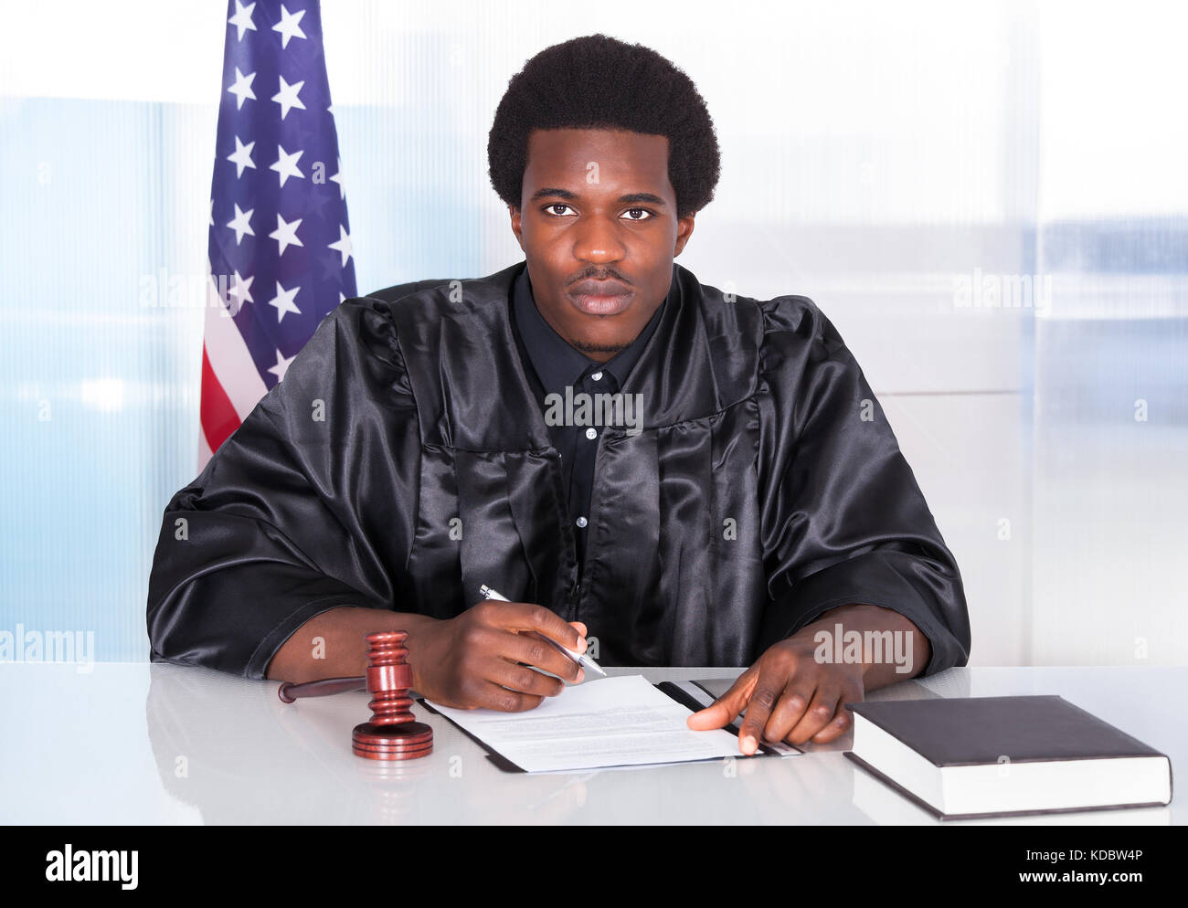 Portrait Of Happy Male Judge Sitting In Courtroom Stock Photo