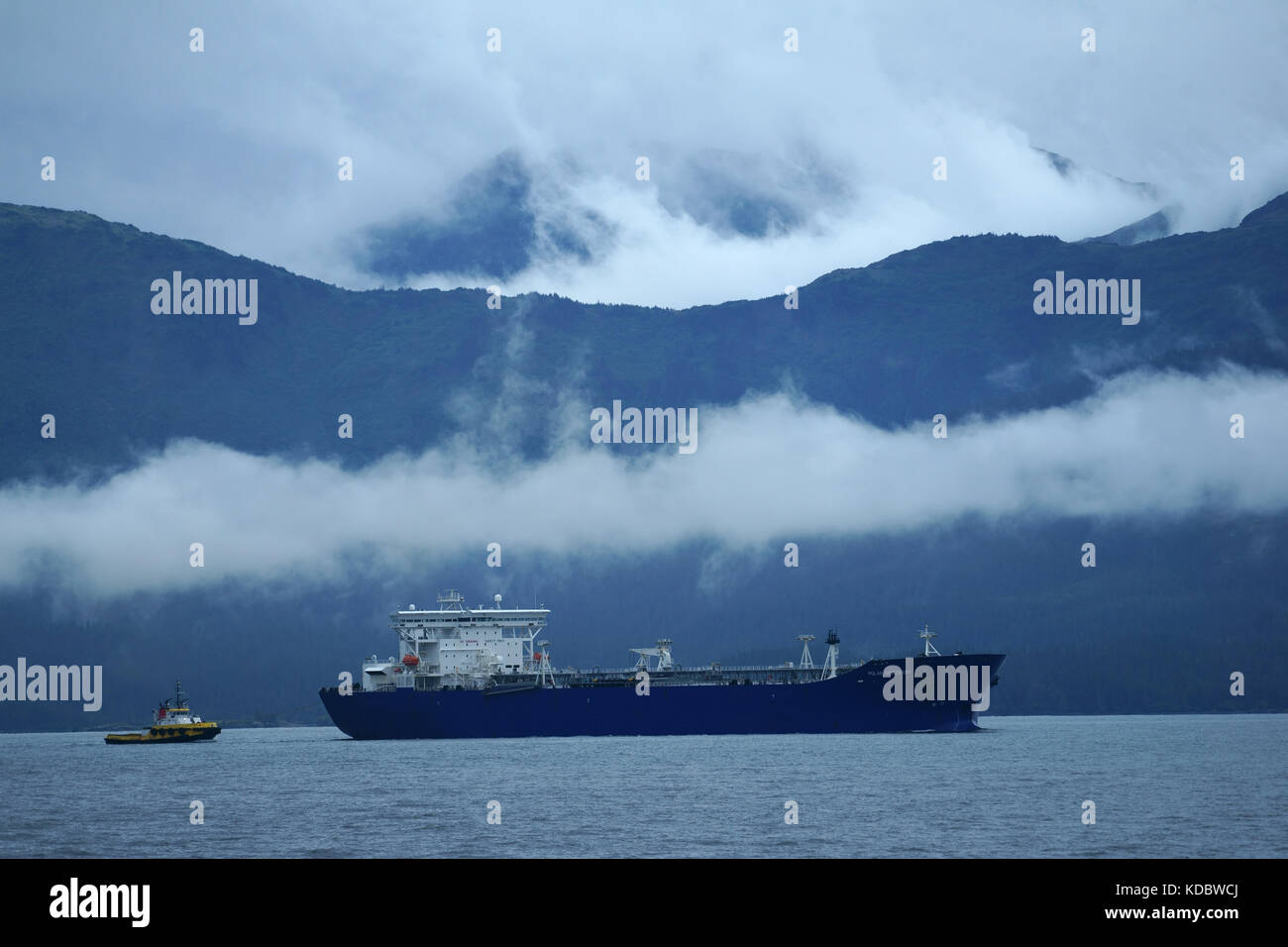 Oil tanker escorted by tugboat through Valdez narrows into Prince William Sound, Alaska Stock Photo