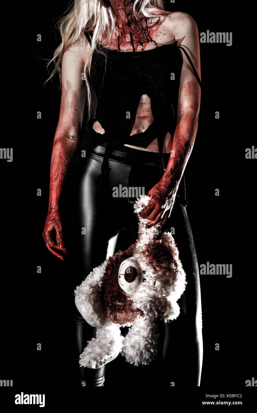 Bloody young woman holding a teddy bear over black background Stock Photo