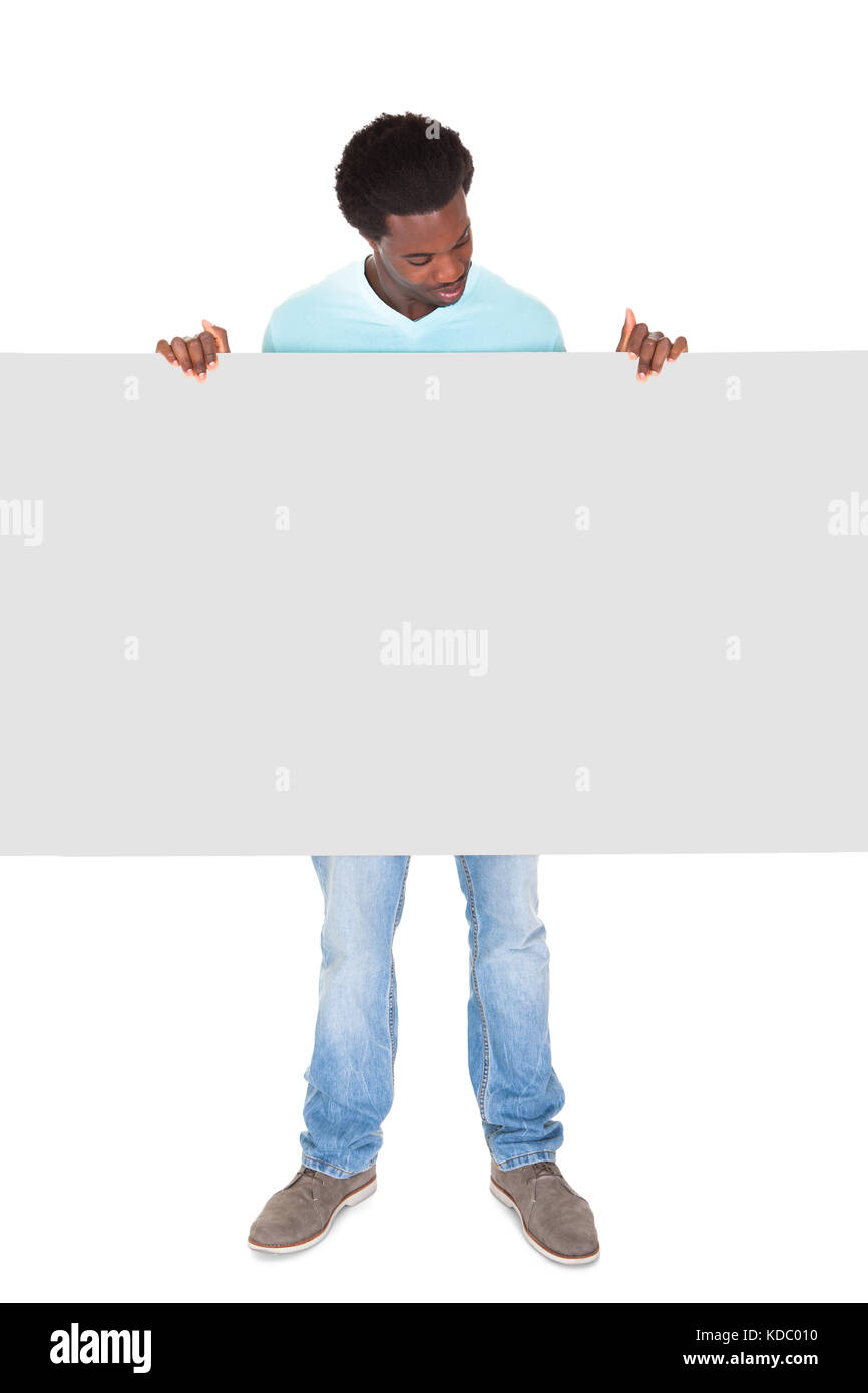 Happy Young African Man In Casual Standing Behind The Placard Over White Background Stock Photo