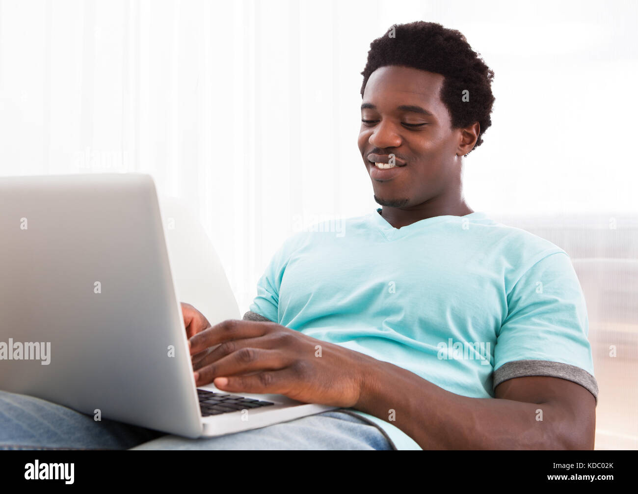 Happy Young African Man Using Laptop Sitting On Couch At Home Stock ...