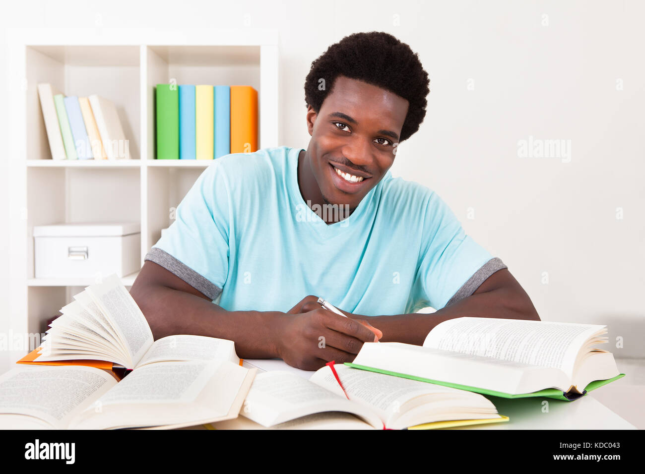 Young African Man Studying At Home With A Lot Of Books Stock Photo