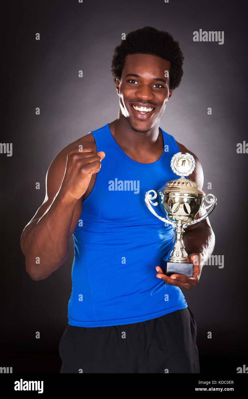 Happy African Man Holding Trophy Over Black Background Stock Photo