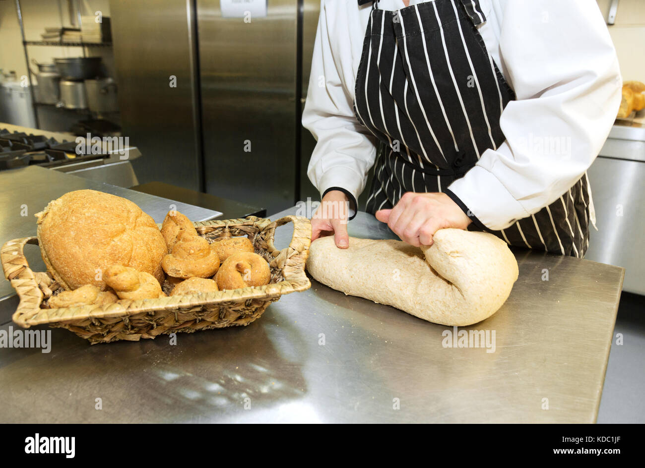 Bread making folding the dough a baker making bread in a bakery, UK