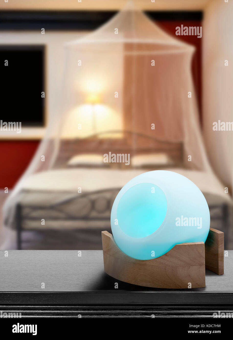 Colored air freshener in glass container in Cosi vintage bedroom with mosquito Net Stock Photo