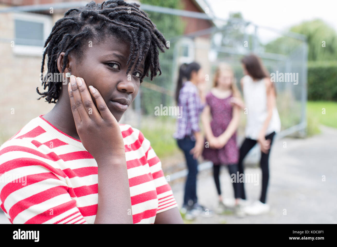 Portrait Of Sad Teenage Girl Feeling Left Out By Friends Stock Photo