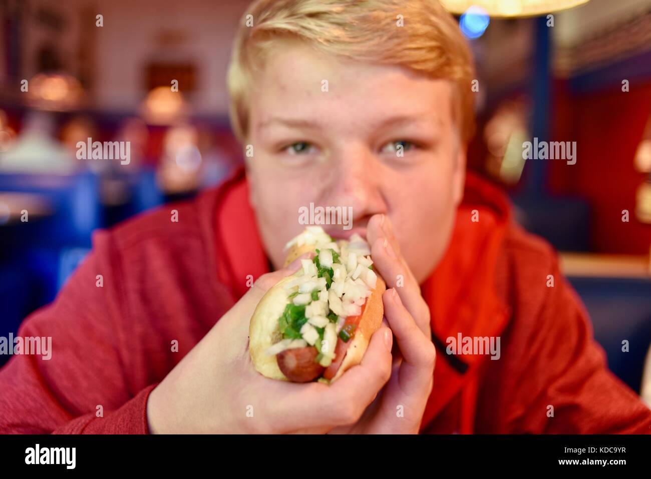 Teenager boy biting into a large hot dog with onions and relish at Wilson's Restaurant in the Door County community of Ephriam, Wisconsin, USA. Stock Photo
