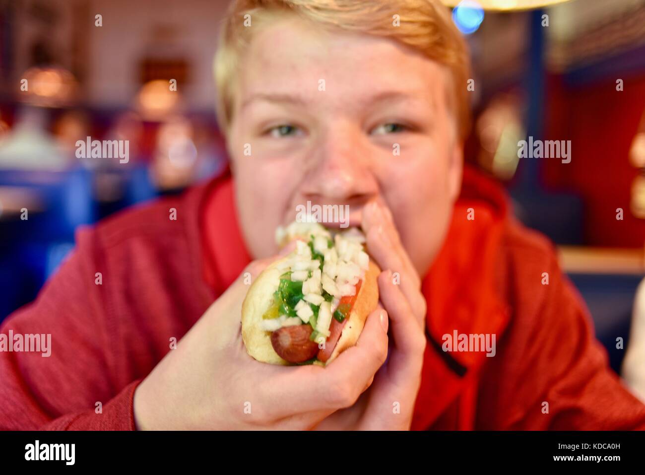 Teenager boy biting into a large hot dog with onions and relish at Wilson's Restaurant in the Door County community of Ephriam, Wisconsin, USA. Stock Photo