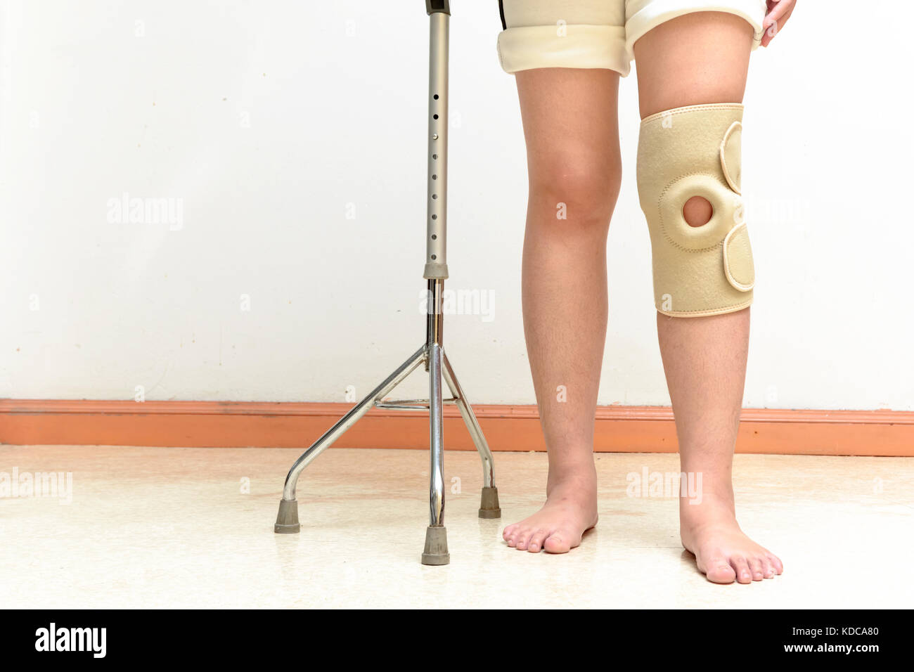 Woman walking on crutches, wearing knee support in rehab center Stock