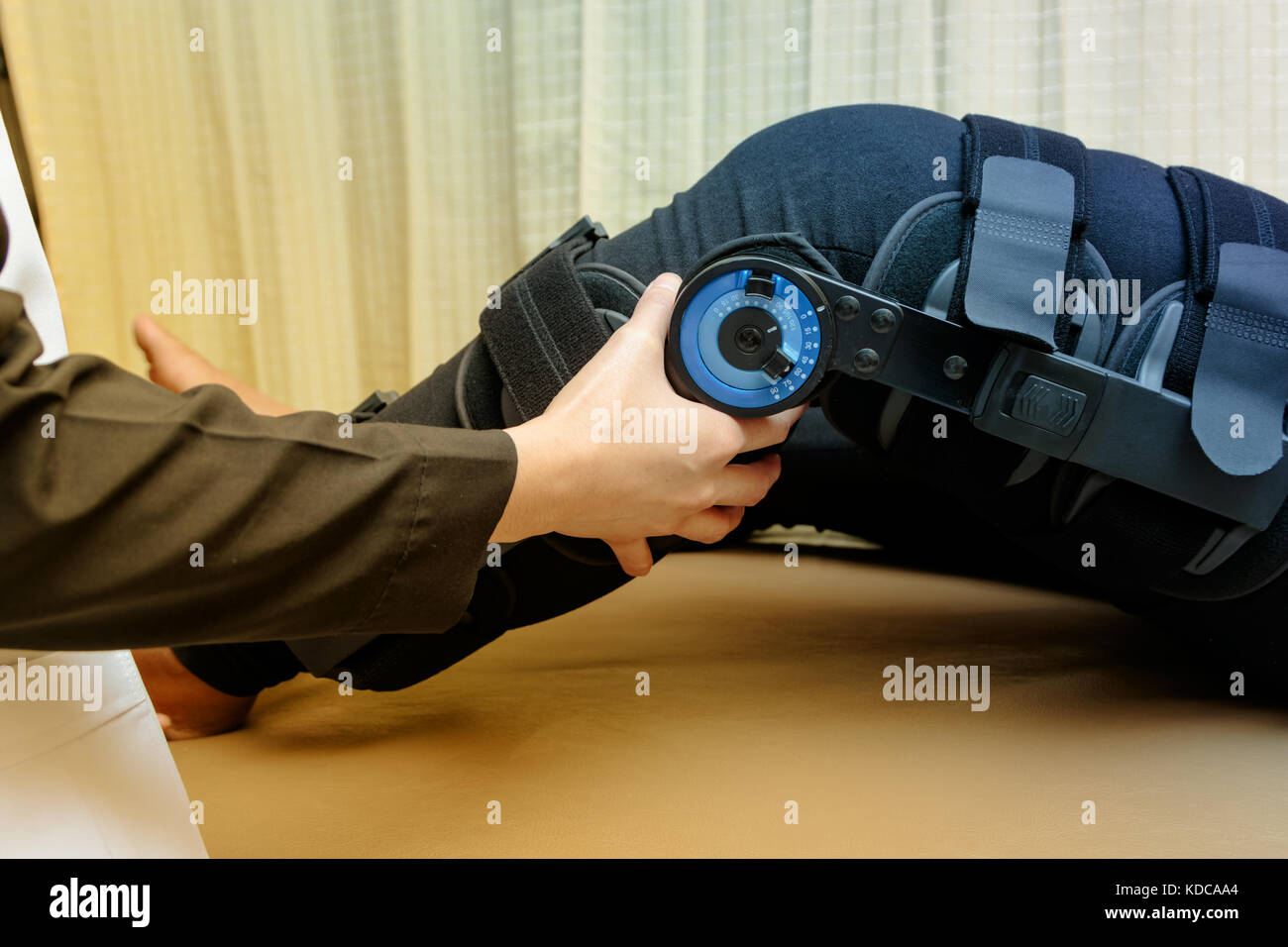 Physiotherapist adjust knee braces on patient 's leg in hospital Stock