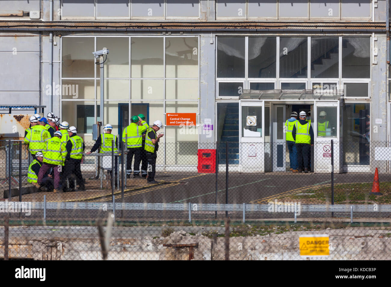Workmen in reflective vests seen outside the dungeness nuclear power plant Stock Photo