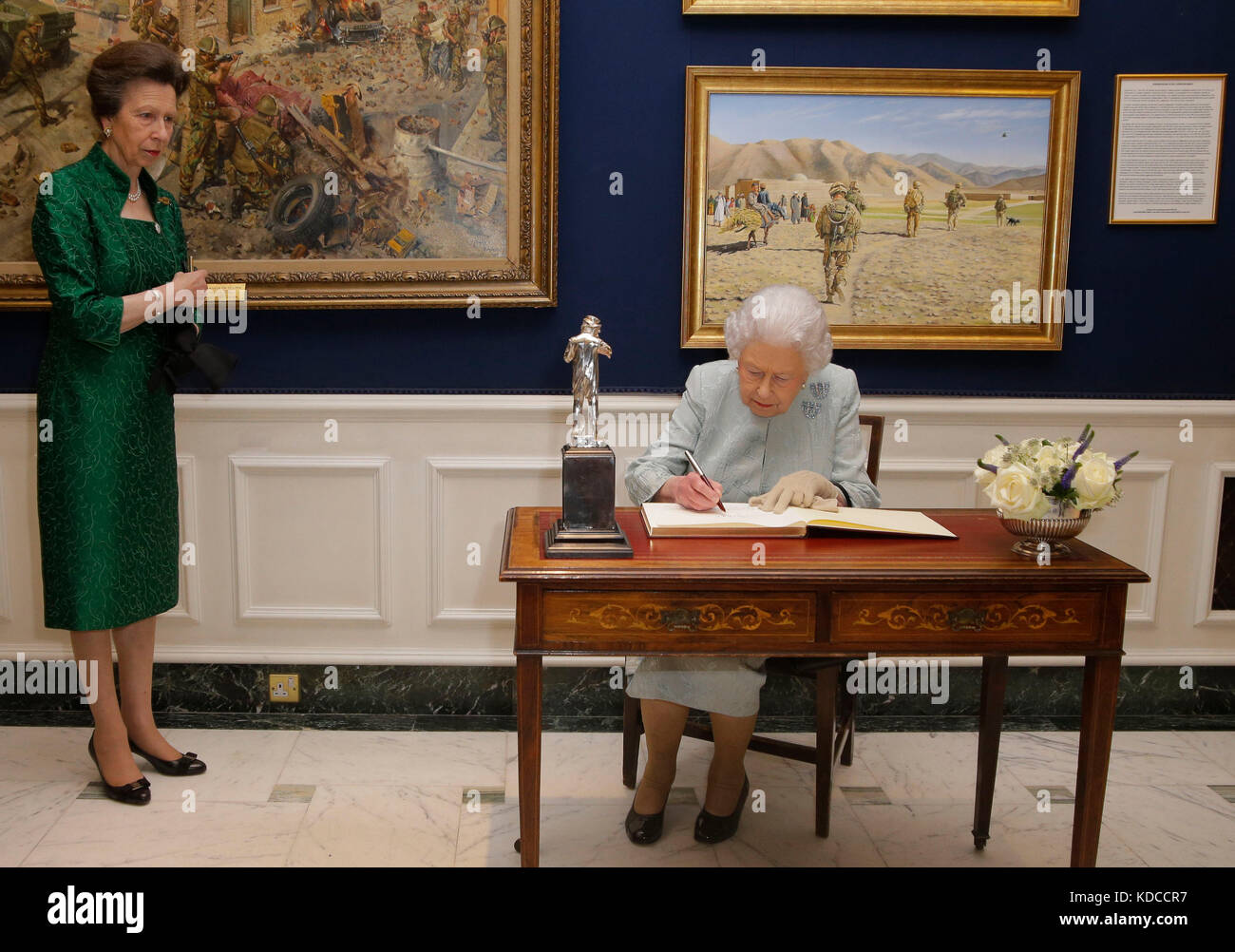 Queen Elizabeth II, accompanied by the Princess Royal, signs the visitors book, during a reception at the Army and Navy Club in central London, to mark the centenary of the Women's Royal Navy Service and the Women's Auxiliary Army Corp. Stock Photo