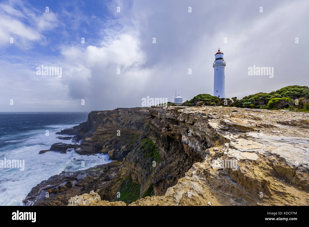 Cape Nelson lighthouse standing on a rugged cliff above ocean under stormy skies. Victoria, Australia. Stock Photo
