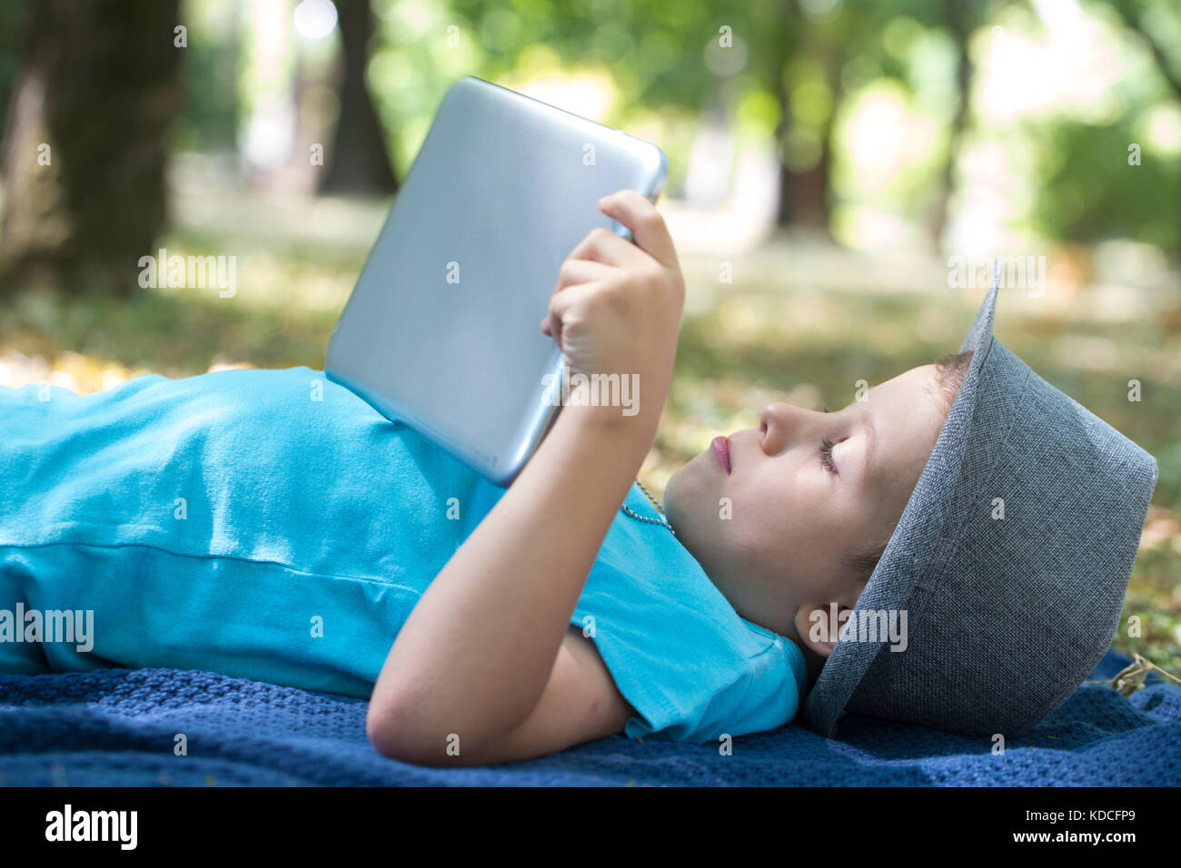 little cute boy of pre-school age uses a digital tablet while lying on ...