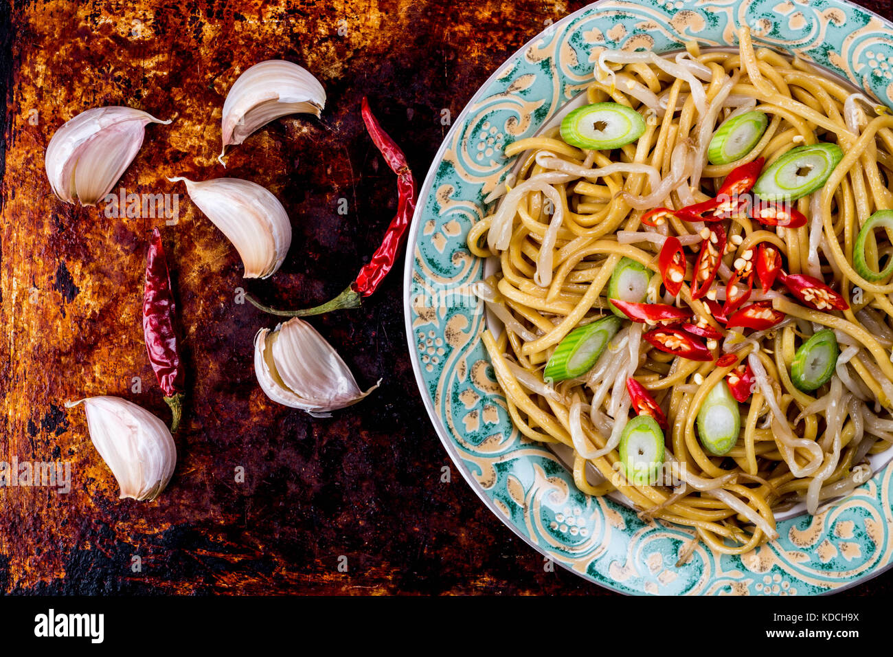Chinese Style Wok Stir Fried Egg Noodles with Beansprouts and Red Chilli On A Distressed Oven or Baking Tray Stock Photo