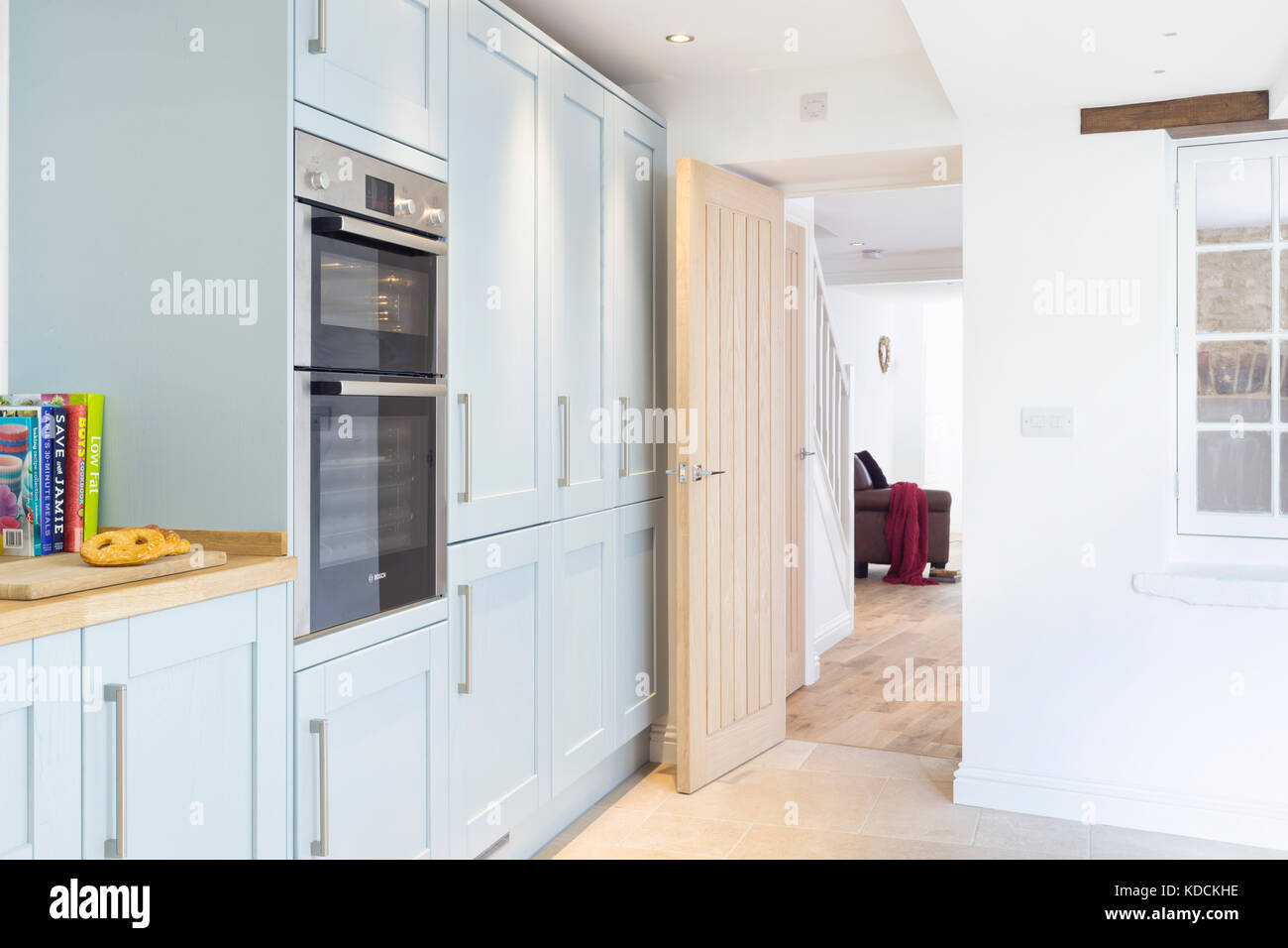 Bespoke fitted kitchen cabinets & double oven in a redeveloped period home, with a view through to other reception rooms Stock Photo