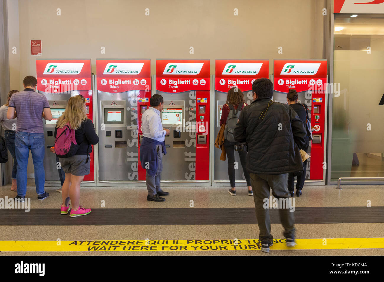 Passengers using Italian Trenitalia automatic indoor self service train ticket vending machines to purchase their tickets at Santa Lucia Station, Veni Stock Photo