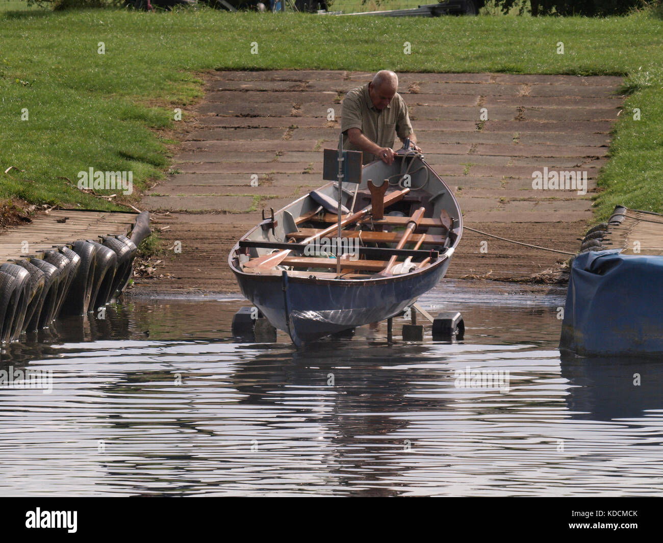 Man Launching a rowing boat on a trailer from slipway, Tewkesbury, Gloucestershire, UK Stock Photo
