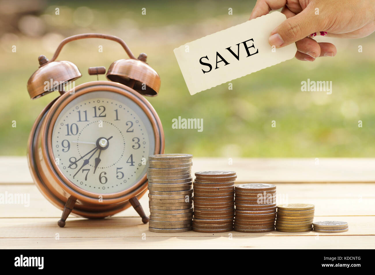 hand holding sign of save on coins and clock on table, concept in save, investment and finace in business Stock Photo