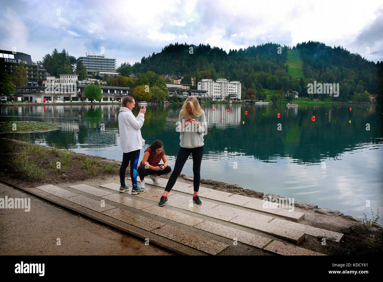 Young women using smart phones beside Lake Bled, Bled, Slovenia. Stock Photo