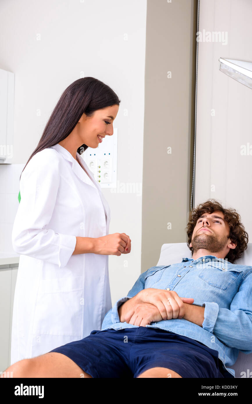 A young male patient in the emergency room getting attended by a female professional physician. Stock Photo