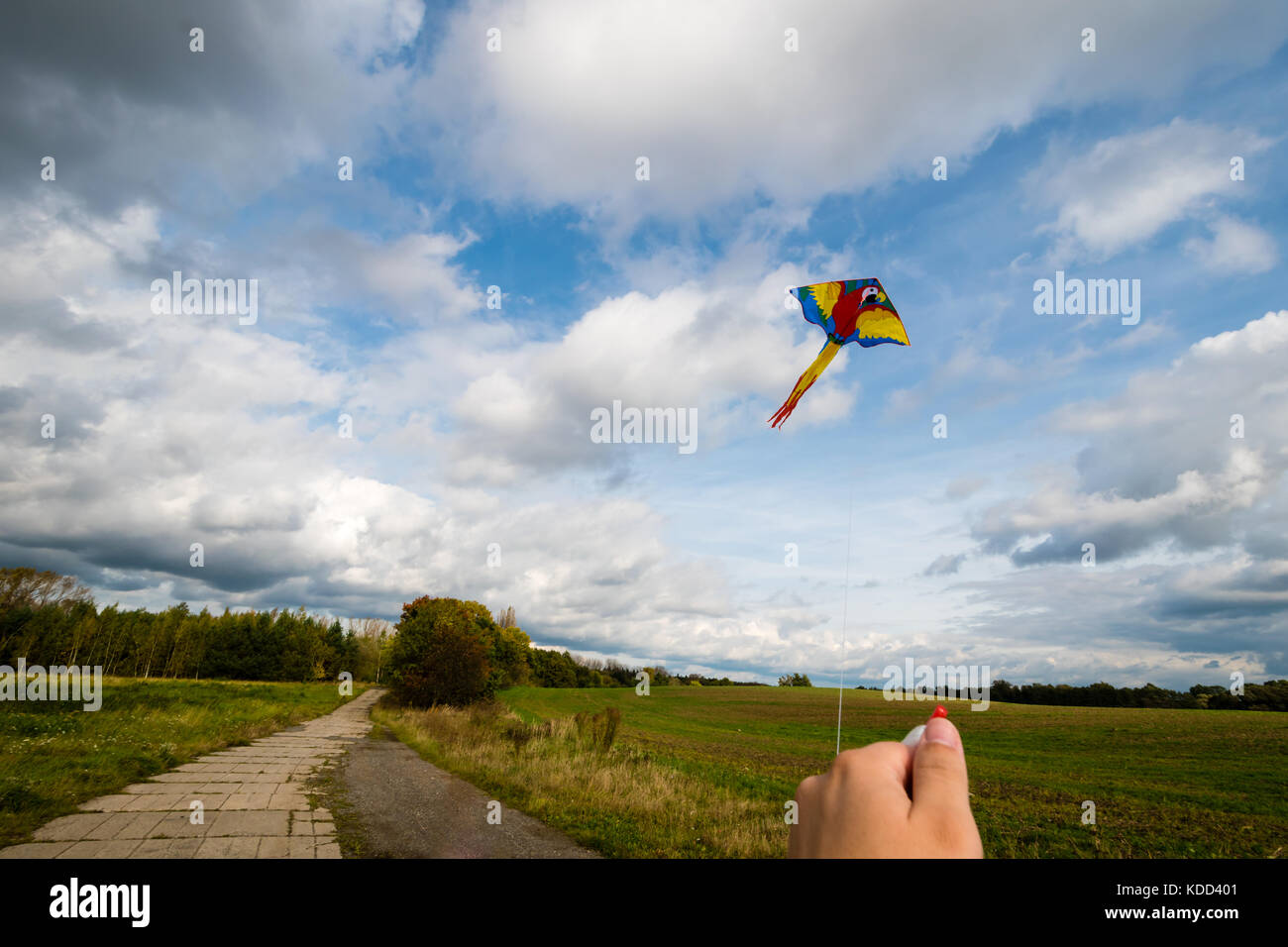 Kite flying in the air. Beautiful sky with clouds on background. Hand holding a string Stock