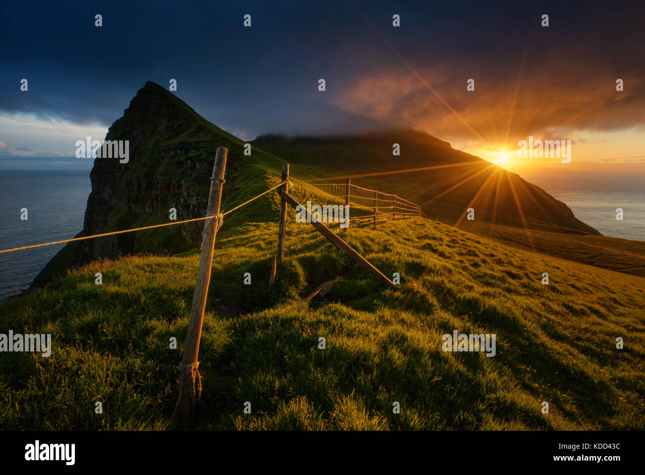 Meadows, mountains and fences on Mykines island in sunset, Faroe Islands Stock Photo