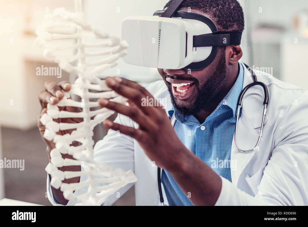 Excited young practitioner in virtual reality glasses touching DNA model Stock Photo